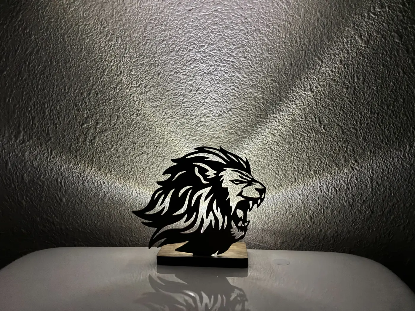 Lion basswood tea-light display casting light onto the wall